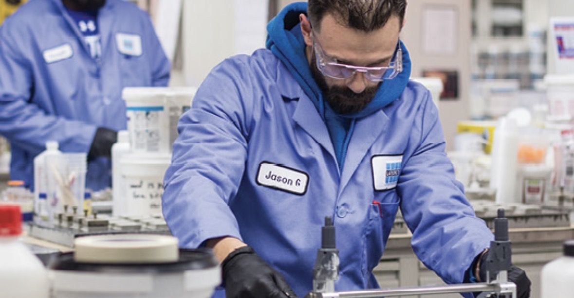 LATICRETE lab technician in a blue lab coat and safety glasses testing product samples