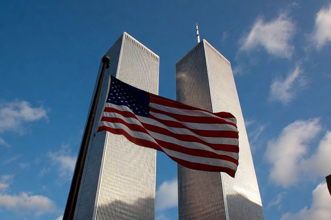 Visualization of the original World Trade Center Twin Towers with an American flag in the foreground